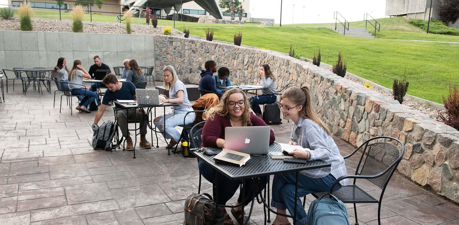 Students studying outside at table on patio